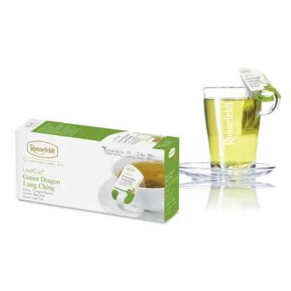 Opakowanie herbaty Ronnefeldt LeafCup Green Dragon Lung Ching obok szklanki z przygotowaną herbatą. Herbata Green Dragon Lung Ching to jasna herbata z mieszanką przypraw, oferowana w eleganckim pudełku z 15 torebkami herbaty, idealna do przygotowania aromatycznego napoju z mieszanką korzennych smaków. Obok znajduje się przezroczysta szklanka z logo Ronnefeldt, ukazująca napój o bogatej, jasnej barwie.