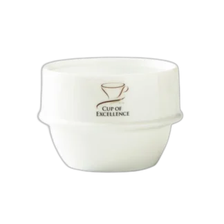 Biała miseczka cuppingowa Origami z logo Cup of Excellence, stworzona z wysokiej jakości ceramiki. Idealna do profesjonalnych degustacji kawy, zapewniająca doskonałe właściwości termiczne i precyzyjne testowanie aromatu oraz smaku kawy.