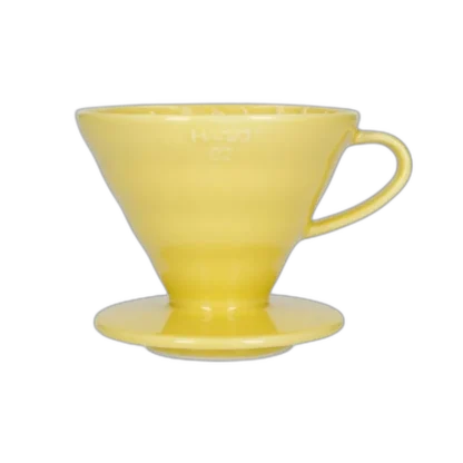 Klasyczny ceramiczny dripper Hario V60-02 w żywym żółtym kolorze, zaprojektowany do precyzyjnego parzenia kawy metodą pour-over. Stożkowy kształt i spiralne żłobienia wewnętrzne zapewniają optymalną ekstrakcję, podkreślając bogaty smak i aromat kawy.