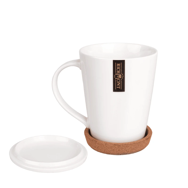 Biała filiżanka do kawy z logo Richmont, idealna do serwowania napojów. W zestawie znajduje się praktyczna podstawka z korka, która chroni powierzchnie przed odciskami.